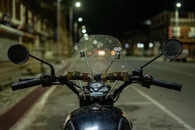 Vue nocturne depuis le poste de pilotage d'une moto équipée d'un pare-brise Honda sous un éclairage urbain.