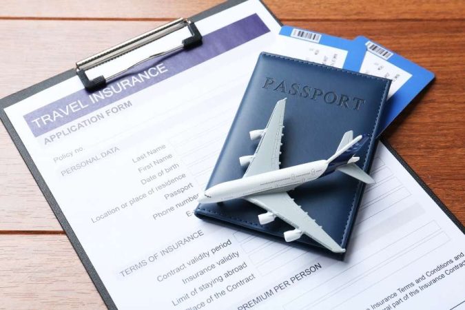 Un formulaire de demande d'assurance voyage posé à côté d'un passeport avec une figurine d'avion.
