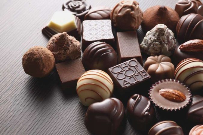 Un assortiment varié de chocolats fins et de truffes disposés sur une surface sombre pour mieux conserver son chocolat.