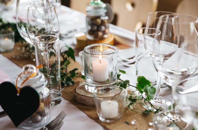 Décoration de table élégante avec bougies allumées, lierre et verrerie fine pour illustrer comment faire un mariage chic et raffiné.